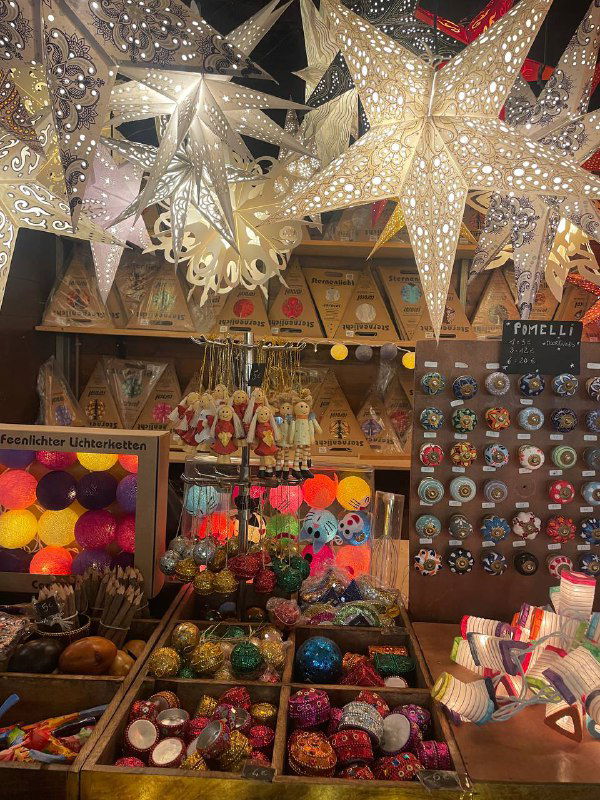 Рождественские бумажные звёзды и светильники на прилавке: декоративные лампы и светящиеся гирлянды среди праздничной витрины.