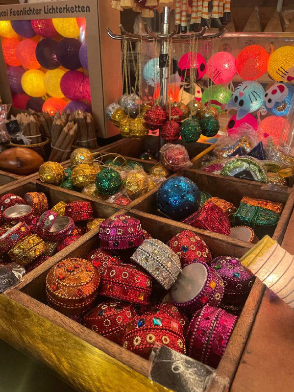 Коробки и миски с разноцветными блестящими шарами и декоративными предметами для праздника: традиционный ассортимент рождественского базара.