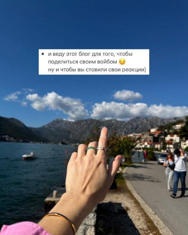 Рука с кольцами указывает на прибрежный городок и горы вдали, снимок символизирует планы и виды для прогулок по побережью в путешествиях автора и её маршрутах.