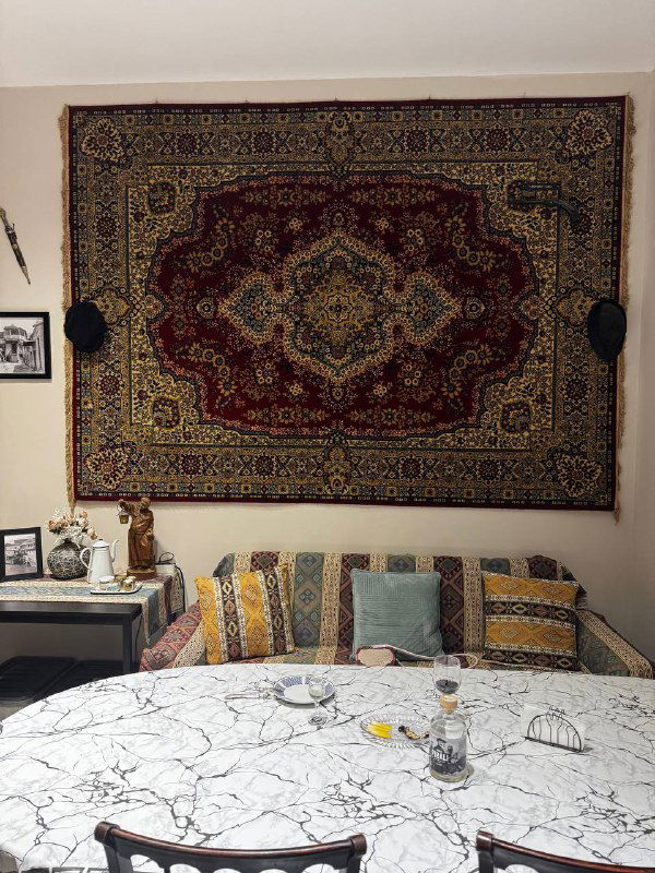 Интерьер комнаты мастер-класса: кровать, декоративный грузинский ковер на стене и уютная обстановка, где проходил кулинарный урок.