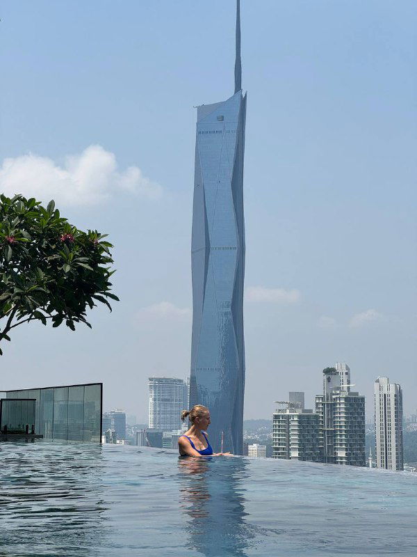 Вид с небоскрёба на городской бассейн и панораму: человек в бассейне на фоне высотных зданий и современного горизонта — ощущение мегаполисного отдыха.