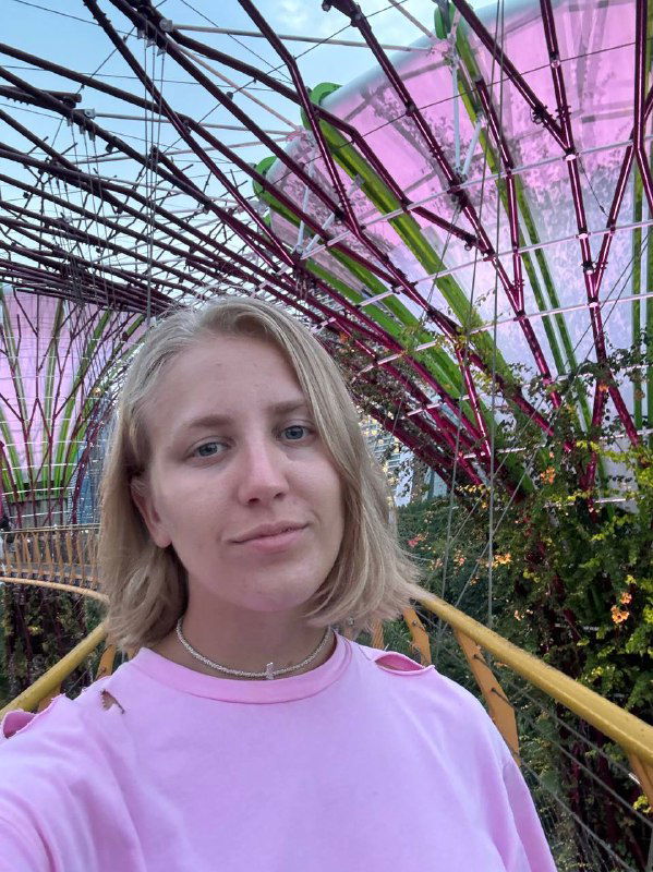 Портретное селфи Маши на фоне футуристических цветных конструкций садов у залива: крупный план лица и архитектурный фон — впечатление от Сингапура.