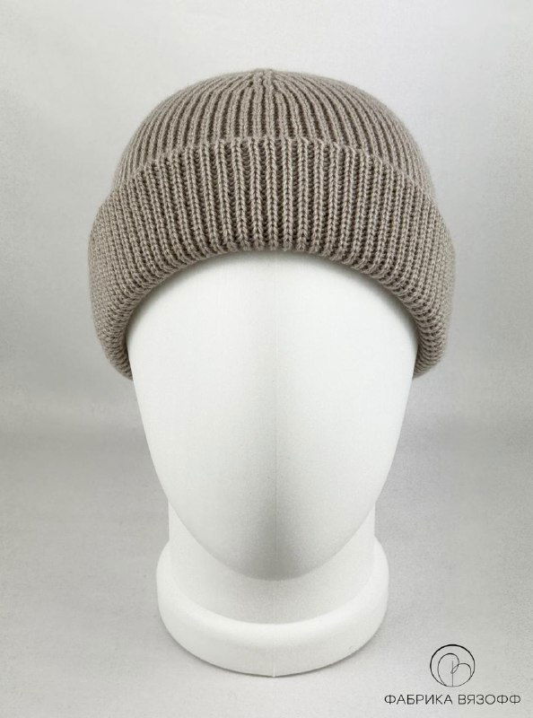 Вязаная шапка бежевого цвета на белом манекене, фронтальный ракурс; видно ровное полотно и плотность вязки, нейтральное студийное освещение.