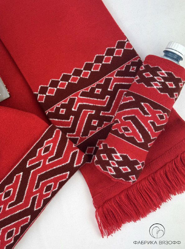 Крупный план орнамента на шарфе и чехле для бутылки — красно‑белые геометрические мотивы и фактура трикотажа.