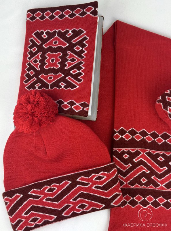 Вид сверху на красный вязаный комплект: обложка, шарф и шапка с характерным национальным орнаментом в едином дизайне.