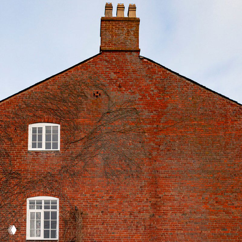 Фасад кирпичного дома с окнами разного размера — пример традиционной архитектуры и расположения окон в старинных постройках.
