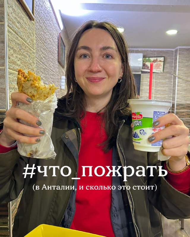 Автор канала держит в руках обёрнутую шаву и стакан йогурта/айрана, улыбается — фотография путешествия и еды в Анталии.