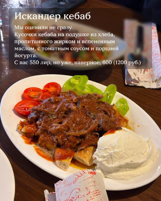 Искандер кебаб на тарелке с томатами и порцией йогурта, кусочки мяса на хлебной подушке — классическое блюдо в турецком ресторане.