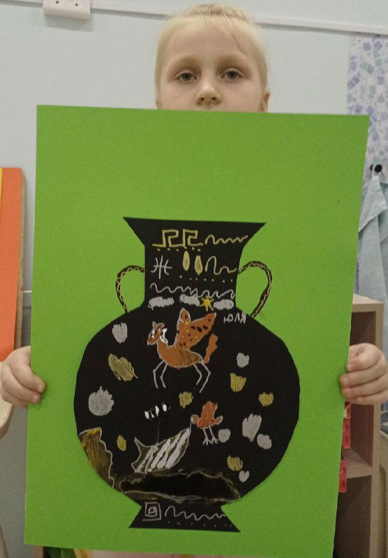 Детская работа — чернофигурная ваза на зеленом фоне, украшенная нарисованными персонажами и орнаментом, аккуратно вырезанная и наклеенная.