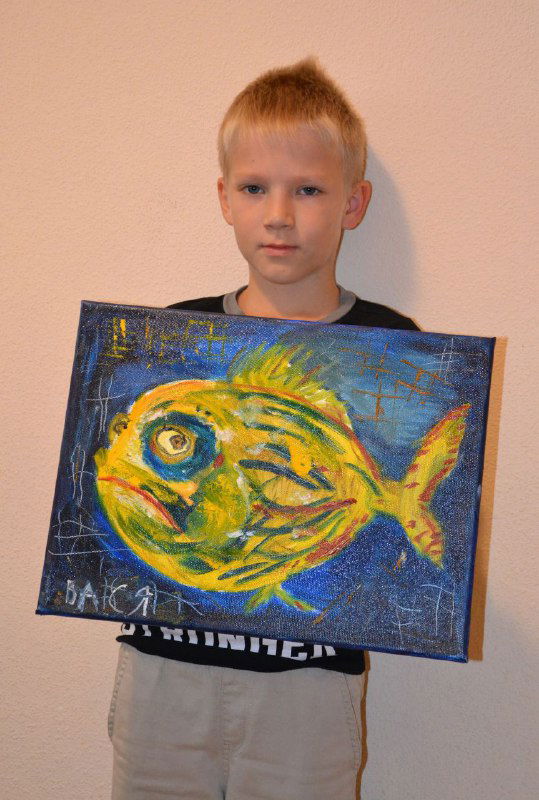 Мальчик показывает яркую декоративную картину с изображением рыбы, детская творческая работа с выразительными мазками и насыщенными оттенками краски