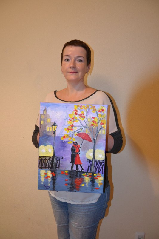 Женщина показывает холст с парой под зонтом на набережной, мягкие отражения и контрастные силуэты в городской миниатюре, студийная фотография