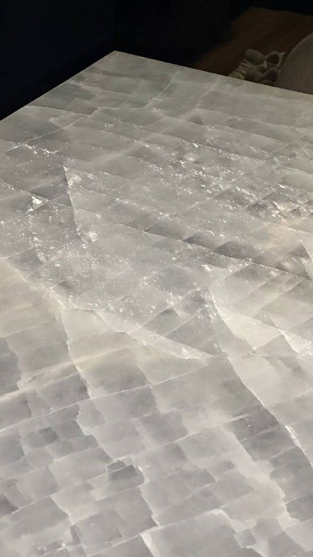 Поверхность ониксовой столешницы под углом, видны кристаллические структуры камня и мягкие отражения света на плоскости.