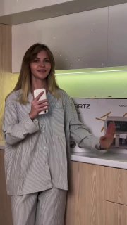 Женщина в пижаме на кухне с коробкой техники GARTZ на фоне — кадр, иллюстрирующий распаковку и демонстрацию бытового прибора в кухонном интерьере.