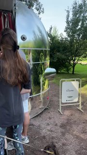 Алюминиевый трейлер джеллатерии Creamo среди зелёной лужайки и деревьев — мобильная точка с вывеской и посетителями в очереди.