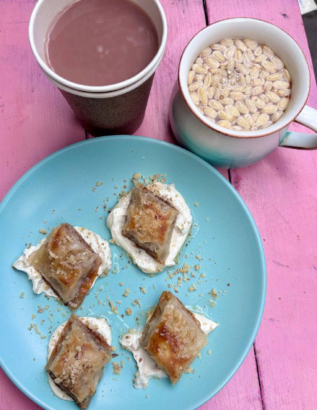 Чашка с горячим какао и кружка с белым кофе рядом с тарелкой с маленькими десертами — тонкая подача на голубой тарелке.