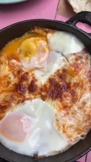 Крупный план шакшуки в другой подаче — запечённые яйца с сыром в сковороде, мягкий желток и золотистая корочка сыра в центре кадра.