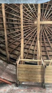 Внутренний каркас овального купола: деревянные балки и конструкция чернового покрытия, вид с галереи под куполом на музейные элементы реставрации.