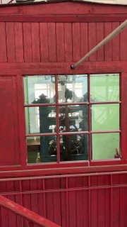 Красная будка часовщика с видимым через окно механизмом больших башенных часов; интерьер служебного помещения внутри часовой башни вокзала.