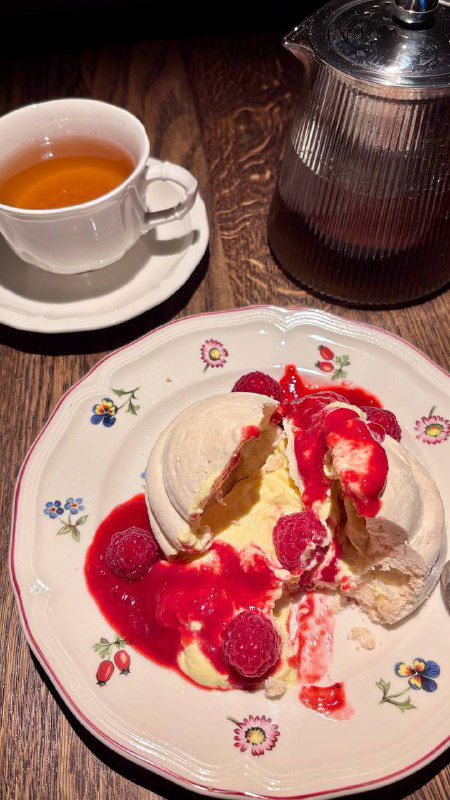 Десертная тарелка с павловой, кукурузным кремом и малиной; сверху видны джем и расплавленный крем — яркие контрасты цветов