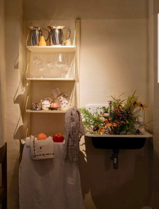 Уютный уголок интерьера с полкой, цветами и раковиной — скандинавский минимализм и текстуры белых тканей в декоре ресторана