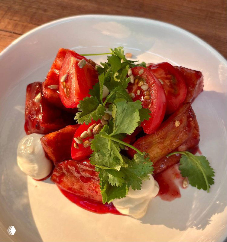 Яркая тарелка с томатным салатом, соусами и зеленью — современная закуска в грузинском стиле, поданная в ресторане Bagebi на Пречистенке.