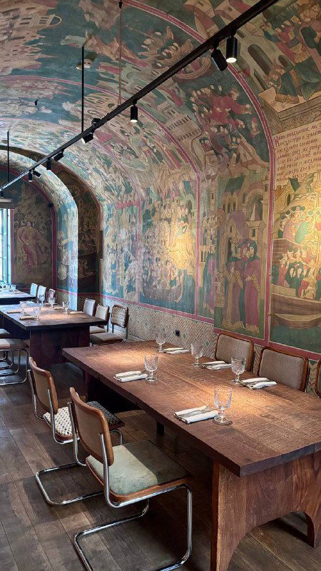 Погребной зал с расписными арками и витражами, длинными деревянными столами и атмосферной подсветкой — интерьер нижнего этажа Bagebi.