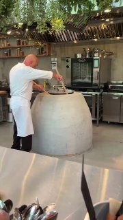 Повар у большого тандыра в открытой пекарне, процесс выпечки шота пури на глазах гостей — работа кухни Bagebi в одноимённом пространстве.