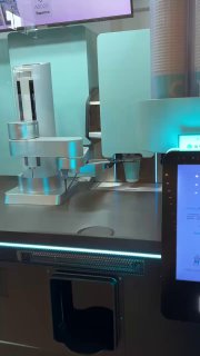 Крупный план механики автомата и сенсорного экрана для заказа, видно рабочие узлы, отсеки для ингредиентов и интерфейс выбора напитка.