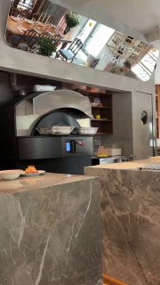 Фрагмент открытой кухни: дровяная или пекарская печь в зоне приготовления пиццы и рабочая поверхность ресторана.