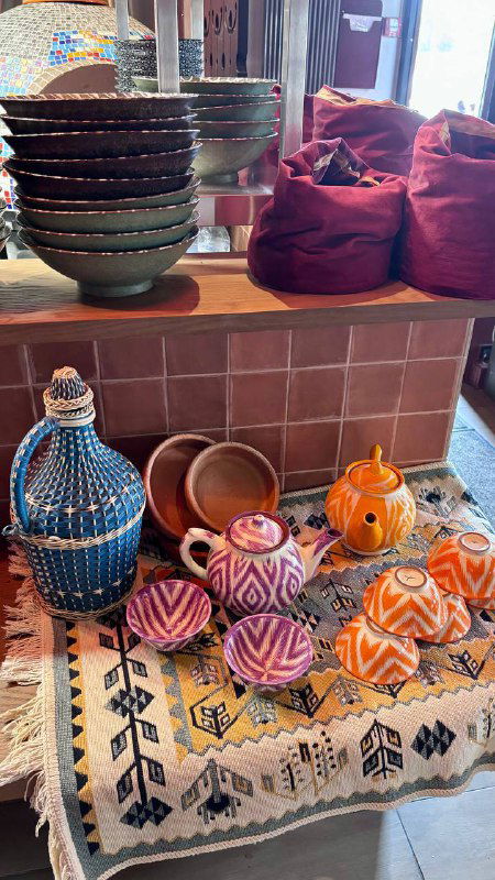 Полка с разноцветной керамикой и тканями в интерьере Kilim: традиционные турецкие сосуды, декор и этнические элементы в зоне бара.