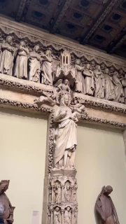 Статуя на фоне орнаментированного деревянного потолка и фигурного карниза: вертикальная композиция с характерной фактурой слепка.