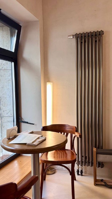 Уютный уголок с круглым столиком и стулом у окна в ресторане Сentrale Bistro — минималистичная посадка и тёплая палитра материалов.