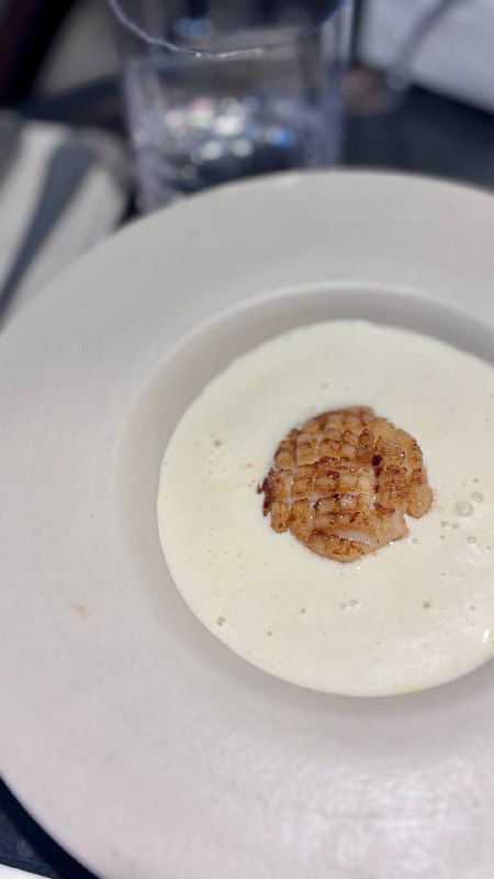 Крупный план гребешка в креме: нежный гребешок на светлом кремовом соусе, акцент на текстуре и подаче блюда в Сentrale Bistro.