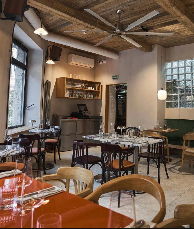 Широкий план пустого зала Сentrale Bistro с деревянными балками на потолке, столиками и барной стойкой — атмосфера простоты и уюта.