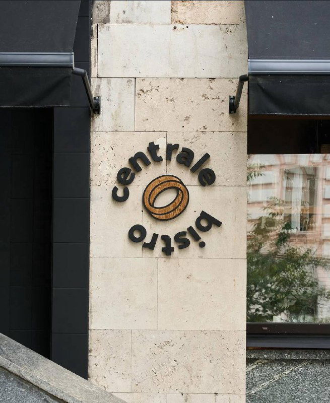 Фасад и вывеска Сentrale Bistro: логотип на светлом каменном фасаде, вход с витриной и уличным видом на Брюсов переулок.
