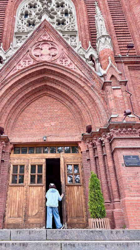 Входная группа собора: массивные деревянные двери, ступени и человек у порога, подчёркивающие масштабы Кафедрального Собора Непорочного Зачатия.