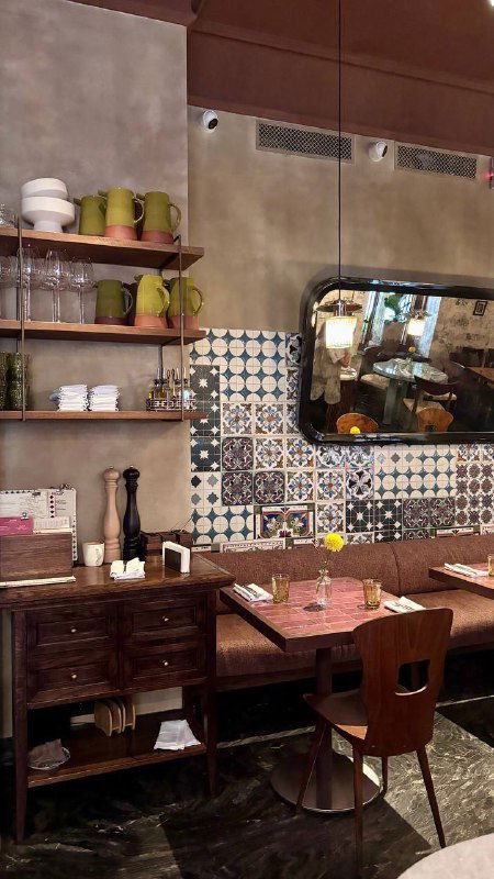 Уголок интерьера бистро с декоративными полками, зеркалом и плиточной стеной — детали оформления и атмосфера заведения.