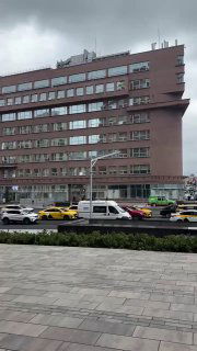 Фасад здания Наркомзема с улицы: многоэтажный корпус, припаркованные автомобили и тротуар на переднем плане, контекст городской застройки Москвы.