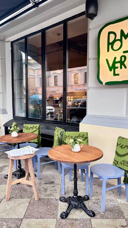 Уличная терраса Pomme Verte: столики у окна, вывеска ресторана и городская улица за стеклом — фасад и уличная посадка заведения.