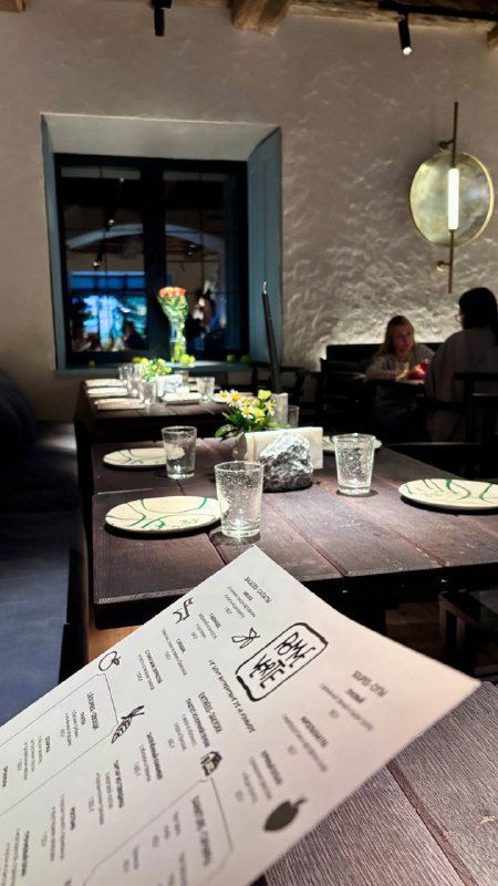 Панорамный кадр внутреннего зала с сервированными столами, скатертями и стеклянной посудой — спокойная вечерняя атмосфера ресторана.