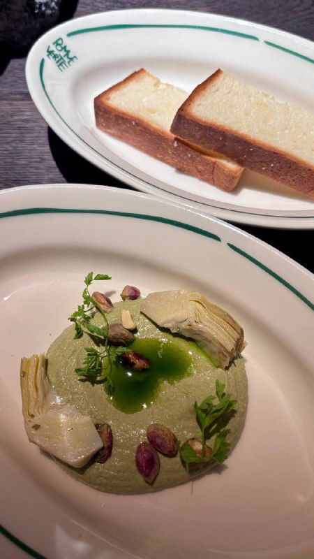 Тарелка с кремом из артишоков, фисташками и декором; снимок крупным планом демонстрирует текстуры и украшения блюда.