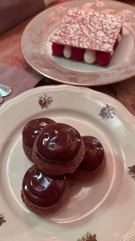 Блестящие шоколадные профитроли с ореховым кремом и шоколадным соусом, аккуратно выложенные на десертной тарелке — звезда вечера.