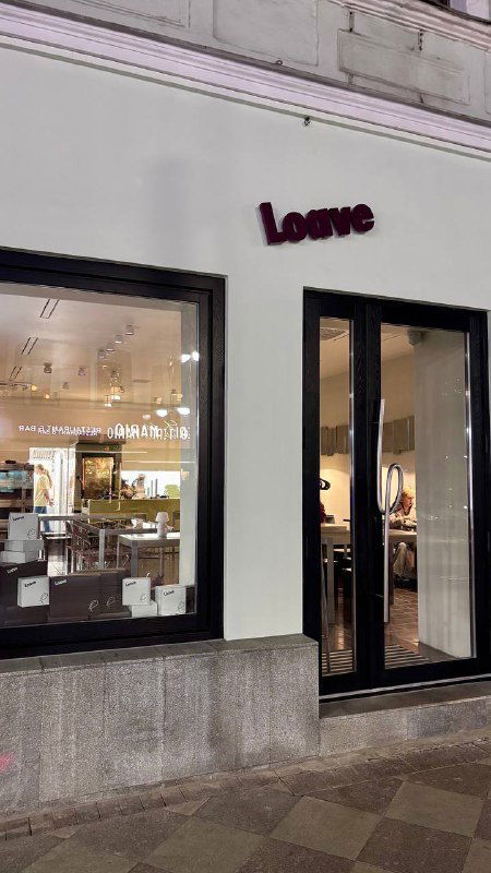 Фасад пекарни Loave с вывеской и витриной в ночной или вечерней подсветке — вид с улицы, вход в заведение.