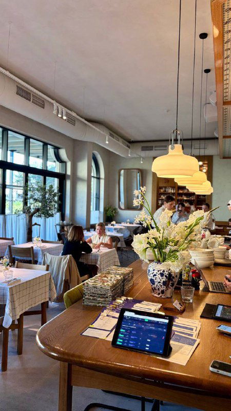 Общий план интерьера ресторана: столы с клетчатыми хлопковыми скатертями, декоративные элементы и мягкое освещение создают уют.