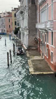 Вид на узкий канал в Венеции с причаленной к набережной гондолой и старинными разноцветными домами, атмосферный городской ракурс днём.