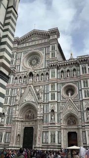 Крупный план фасада Собора Санта Мария дель Фиоре во Флоренции: многоцветный мрамор, орнаменты и розетка над главным входом.