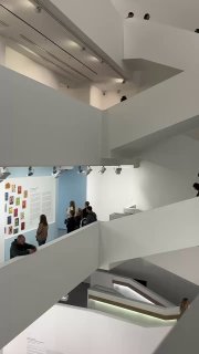 Вид на плавную внутреннюю лестницу и этажи белого интерьера Мультимедиа арт музея Москвы, посетители поднимаются между уровнями экспозиции.