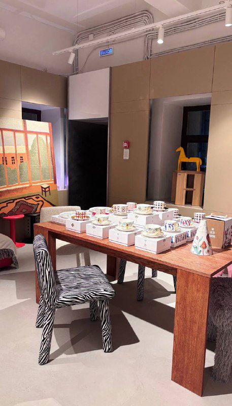 Рабочий стол с сервировкой и предметами интерьера: деревянный стол, стулья и аккуратно расставленные декоративные аксессуары в магазине.