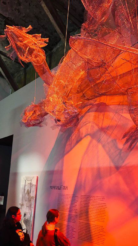 Полупрозрачная оранжево-красная тканевая или плетёная скульптура, подсвеченная изнутри, создающая драматический эффект в зале.