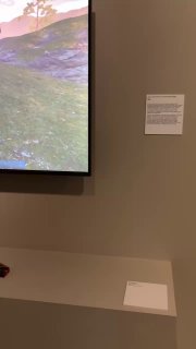 Экран с видеопроекцией и подписью рядом — часть мультимедийного стенда в выставке, минималистичное оформление стенда.